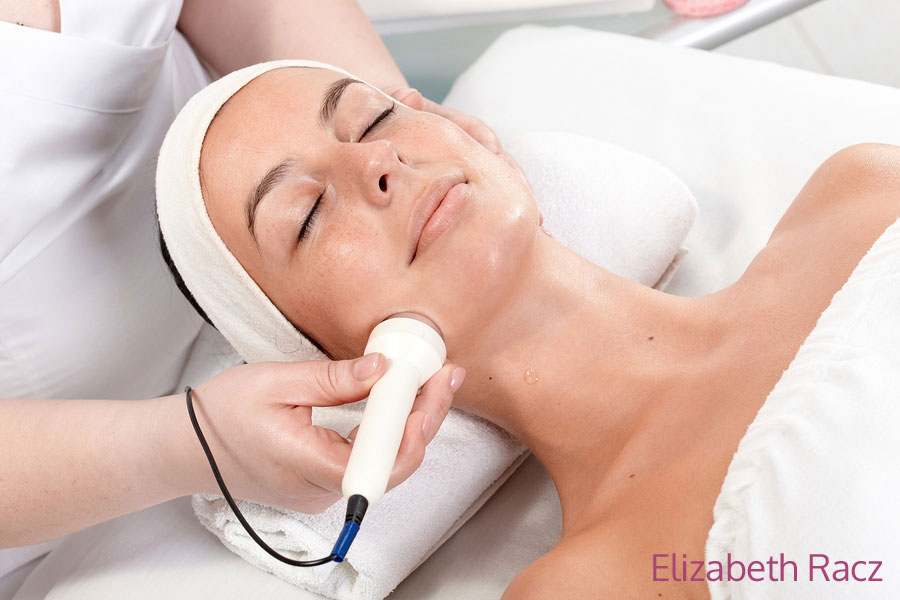 Young woman laying eyes closed, receiving facial beauty treatment